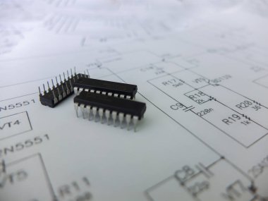 Çeşitli entegre devreler, DIP SOIC TQFP paketlerindeki mikro kontrolörler. Arkasında şematik bir şema var.
