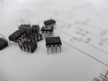 Various integrated circuits, microcontrollers in DIP SOIC TQFP packages. On the back there is a schematic diagram clipart