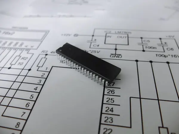 Çeşitli entegre devreler, DIP SOIC TQFP paketlerindeki mikro kontrolörler. Arkasında şematik bir şema var.
