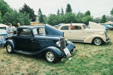 Auburn WA USA, 4 Temmuz 2025 - Klasik bir 4 Temmuz geleneği için klasik ulaşım meraklıları Les Gove Park 'ın antika arabalarına, kamyonlarına ve motosikletlerine hayran kalabilirler