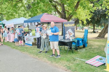 Auburn WA USA, 4 Temmuz 2025 - Parktaki bir festivalde yiyecek ve hediyelik eşya satıyor. İnsanlar parkta bir festival fuarında yürüyorlar..