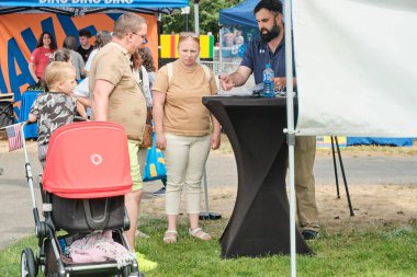 Auburn WA USA, 4 Temmuz 2025 - Parktaki bir festivalde yiyecek ve hediyelik eşya satıyor. İnsanlar parkta bir festival fuarında yürüyorlar..