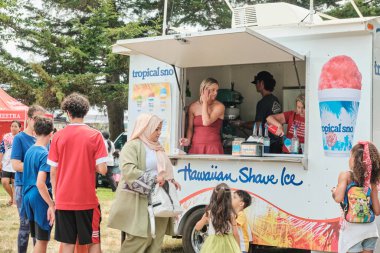 Auburn WA USA, 4 Temmuz 2025 - Parktaki festivalde yiyecek ve hediyelik eşya tezgahları. İnsanlar seyyar tezgahlardan yiyecek alıyor.