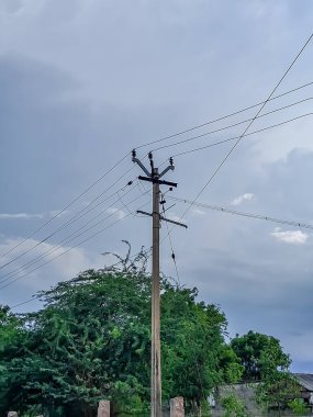 Elektrik kablolarıyla elektrik direği beyaz bulutlu temiz bir gökyüzüne karşı, Hindistan.