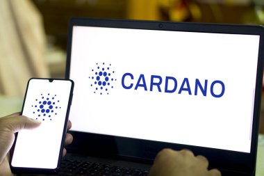 Akıllı telefon ve dizüstü bilgisayarda Cardano kripto para birimi logosu görüldü..