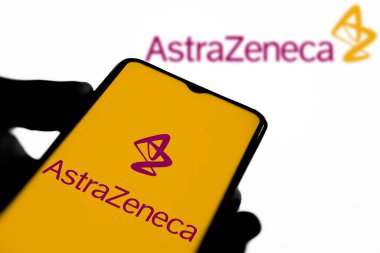 Dhaka, Bangladeş 10 Mayıs 2024: Eczacılık şirketi AstraZeneca plc 'in logosuyla cep telefonu tutan kişi.