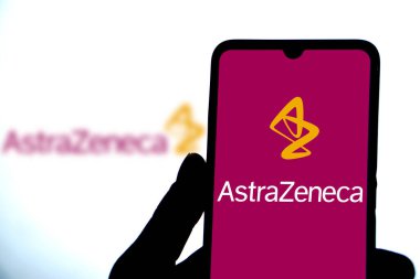 Dhaka,Bangladesh 10 May 2024:Person holding cellphone with logo of pharmaceutical company AstraZeneca plc. clipart