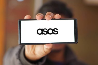 Dhaka, Bangladeş 14 Aralık 2024: İngiliz moda perakende şirketi ASOS plc 'in logosunu taşıyan cep telefonu iş sitesinin önünde ekranda. Telefon ekranının merkez soluna odaklan.