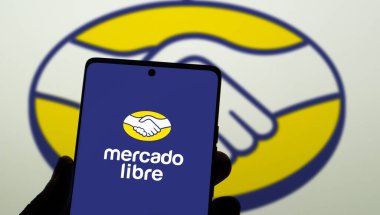 Dhaka, Bangladeş 30 Aralık 2024: Arjantinli e-ticaret şirketi Mercado Libre Inc. 'in logosunu taşıyan cep telefonu, iş dünyasının web sitesi önünde ekranda. Telefon ekranının merkezine odaklan.