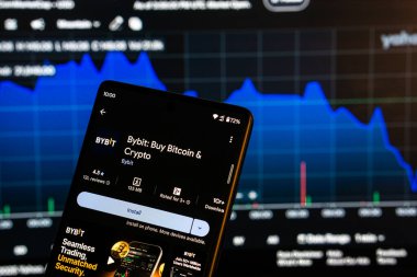 Dhaka, Bangladeş 08 Mart 2025: Bir akıllı telefon üzerindeki Bybit uygulama kurulum ekranı ve arka plandaki finans piyasası grafiği.