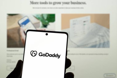 Dhaka, Bangladeş 23 Mart 2025: ABD web sunucu şirketi GoDaddy Inc. 'in logosuyla akıllı telefon sahibi kişi web sitesinin önünde ekranda. Telefon ekranına odaklan.