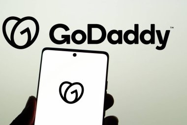 Dhaka, Bangladeş 23 Mart 2025: ABD web sunucu şirketi GoDaddy Inc. 'in logosuyla akıllı telefon sahibi kişi web sitesinin önünde ekranda. Telefon ekranına odaklan.