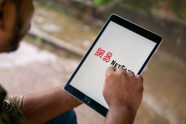 Dhaka, Bangladeş 23 Mart 2025: Cep telefonunda Çinli teknoloji şirketi NetEase Inc. 'in logosu olan kişi ekranda.