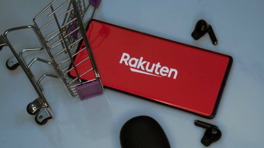 Dhaka, Bangladeş 19 Nisan 2025: Rakuten Group Japon elektronik ticaret ve çevrimiçi perakende satış şirketidir. Rakuten logosunun arka planında paketler olan alışveriş arabası..