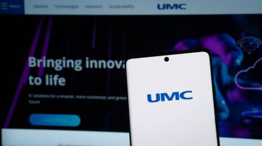 Dhaka, Bangladeş 08 Mayıs 2025: Web sayfası önünde üzerinde United Microelectronics Corporation (UMC) şirketinin logosu bulunan cep telefonu sahibi kişi.
