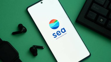 Dhaka, Banglades 24 Mayıs 2025: Bir akıllı telefon ekranında SEA Ltd logosu, kulaklıklar ve yeşil arka planda bir klavye görülüyor.