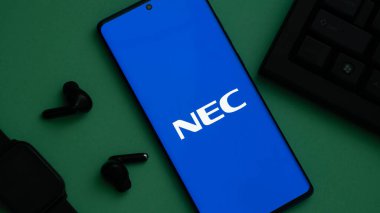 Dhaka, Bangladeş 23 Mayıs 2025: Yeşil yüzeyde kulaklıklar ve klavyelerle çevrili akıllı telefon.