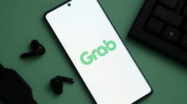 Dhaka, Bangladeş 20 Mayıs 2025: Akıllı telefon yeşil bir zemin üzerinde Kap logosunu ve kulaklıkları gösteriyor.