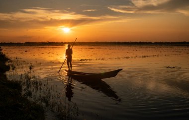 Teknedeki yalnız bir balıkçı için çarpıcı bir günbatımı arkaplanı