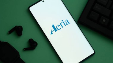 Dhaka, Bangladeş 01 Haziran 2025: 'Aeria' logosunu bir klavye ve kulaklıkların yanında gösteren parlak ekran.