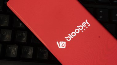 Dhaka, Bangladesh 01 June 2025:Smartphone showing Bloober Team logo on red background with accessories.