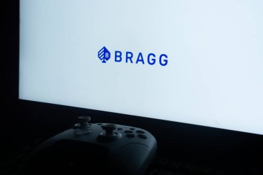 Dhaka, Bangladeş 02 Haziran 2025: Beyaz arkaplanda BRAGG logosu bulunan bir ekranın önündeki oyun konsolu.