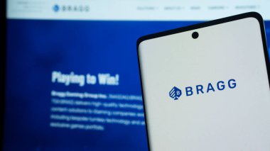 Dhaka, Bangladeş 02 Haziran 2025: Monitördeki bir web sayfasının önündeki akıllı telefon ekranında Bragg logosu.