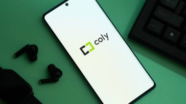 Dhaka, Bangladeş 02 Haziran 2025: Kulaklıkların yanında 'coly' logosu olan akıllı telefon ve yeşil yüzey üzerinde akıllı kaset.