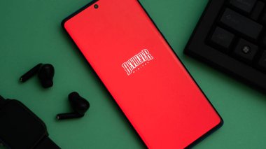 Dhaka, Bangladeş 03 Mayıs 2025: Aksesuarlı kırmızı akıllı telefon ekranında Devolver Dijital logosu.