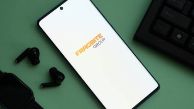 Dhaka, Bangladeş 01 Temmuz 2025: Fragbite Group logosuna sahip akıllı telefon kulaklıklı yeşil yüzey.
