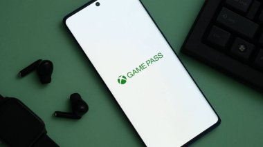 Dhaka, Bangladeş 04 Temmuz 2025: GAME PASS logosunun yer aldığı akıllı telefon kulaklıklar ve akıllı kulaklıklarla çevrili, bir oyun kurulumunun parçası.