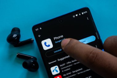 Dhaka, Bangladeş 23 Ağustos 2025: Mavi kulaklıkların yanındaki telefon uygulamaları ile parmak etkileşimi