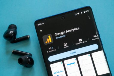 Dhaka, Bangladeş 23 Ağustos 2025: Mavi bir yüzey üzerinde siyah kulaklıklı Google Analitik uygulamasını gösteren akıllı telefon
