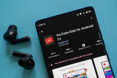 Dhaka, Bangladeş 23 Ağustos 2025: Android TV için YouTube Çocuk uygulaması, siyah kulaklıklar, mavi arkaplan gösteren akıllı telefon ekranı