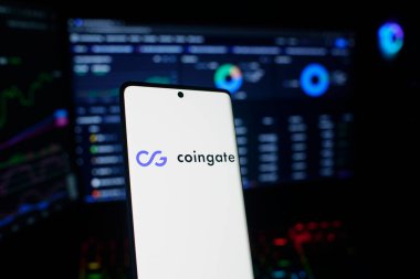 Dhaka, Bangladeş 18 Eylül 2025: Coingate logosu ile telefon, ticari izleme ve madeni paraların arka planında kurulmuş