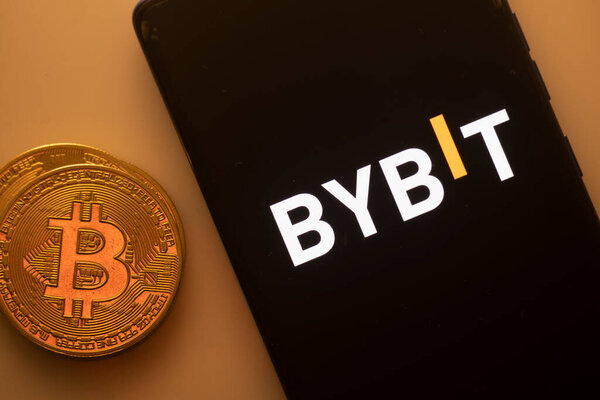Дакка, Бангладеш 22 сентября 2025: Логотип Bybit на черном смартфоне рядом с биткойном на оранжевом фоне