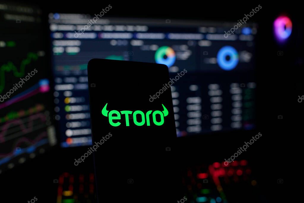 Dhaka, Bangladesh 26 September 2025:Smartphone with eToro logo highlighted against trading screens showing market data