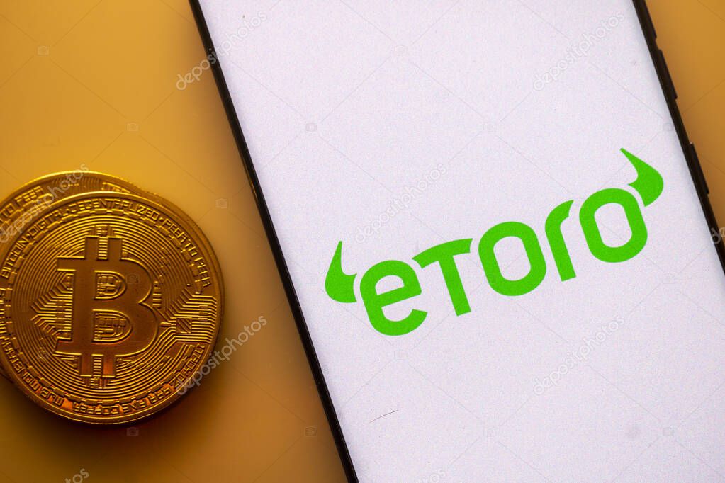 Dhaka, Bangladesh 22 September 2025:Etoro logo on a smartphone screen next to a Bitcoin coin on an orange background