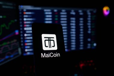 Dhaka, Bangladeş 22 Eylül 2025: Kırmızı zemin üzerinde MaiCoin logosu bulunan bir akıllı telefonun yanında Bitcoin para