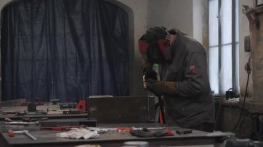 Koruyucu maskeli bir işçi metal parçaları kaynak yapar. Yüksek kalite 4k görüntü
