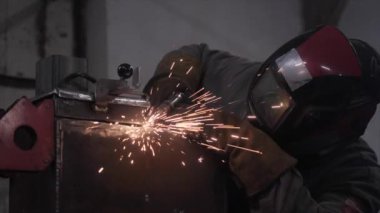 Koruyucu maskeli bir işçi metal parçaları kaynak yapar. Yüksek kalite 4k görüntü