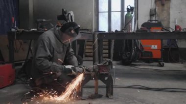 Bir işçi metal bir parçayı öğütür. Kıvılcım saçıyor. Yüksek kalite 4k görüntü