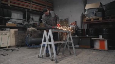 Bir işçi metal bir parçayı öğütür. Kıvılcım saçıyor. Yüksek kalite 4k görüntü