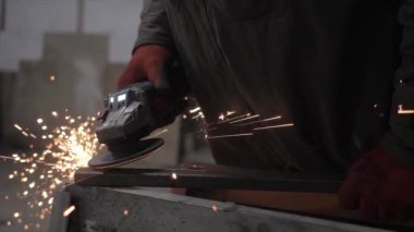 Bir işçi metal bir parçayı öğütür. Kıvılcım saçıyor. Yüksek kalite 4k görüntü