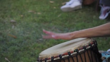 Müzisyen ellerinin djembe davul çalmasını yakından izleyin. Ritim ve kültürle dolu açık hava topluluğu etkinliği.