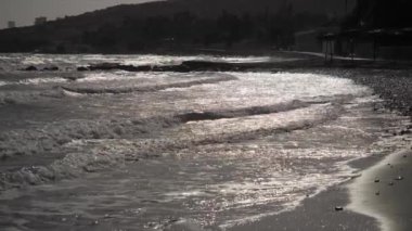 Gün batımında kumlu bir sahile vuran yumuşak okyanus dalgalarının huzur verici manzarası. Rahatlamak için mükemmel..