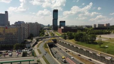 Bu, hareketli şehir binaları ve yemyeşil alanlarla kesişen yoğun bir otoyolu gösteren büyüleyici bir hava manzarası.