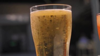 Serinletici bir bardak soğuk biranın yakın plan görüntüsü, canlı altın rengini ve kabarcıklarını gözler önüne seriyor