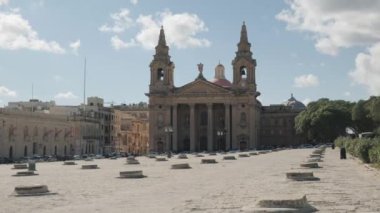 Canlı bir şehir meydanında, berrak mavi gökyüzüyle çevrili tarihi bir binanın nefes kesici manzarası.