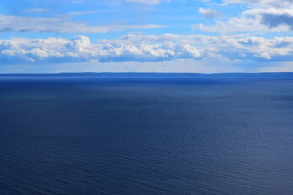 A monochromatic view of only water and sky with some hills on the horizon at lake superior in Canada.